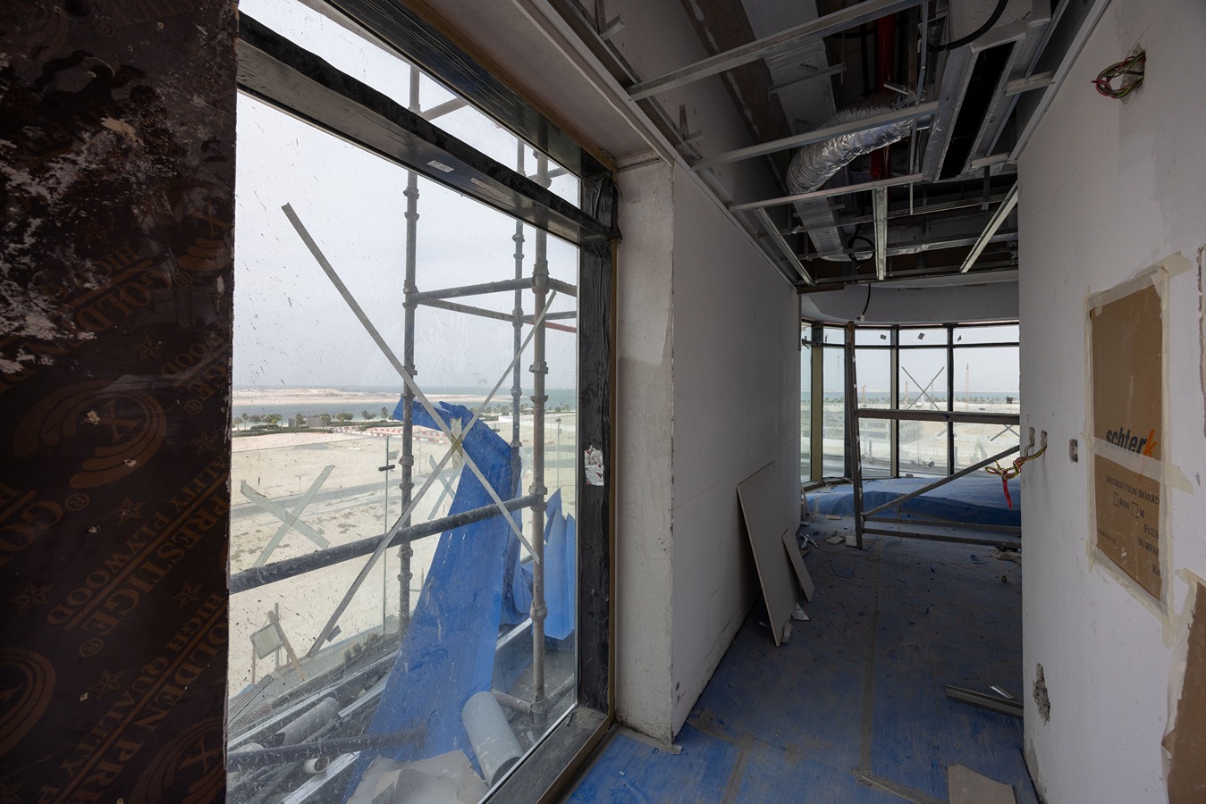 Beach Walk Residence Interior of a construction site featuring exposed walls, scaffolding, and a view of the outside landscape through windows.